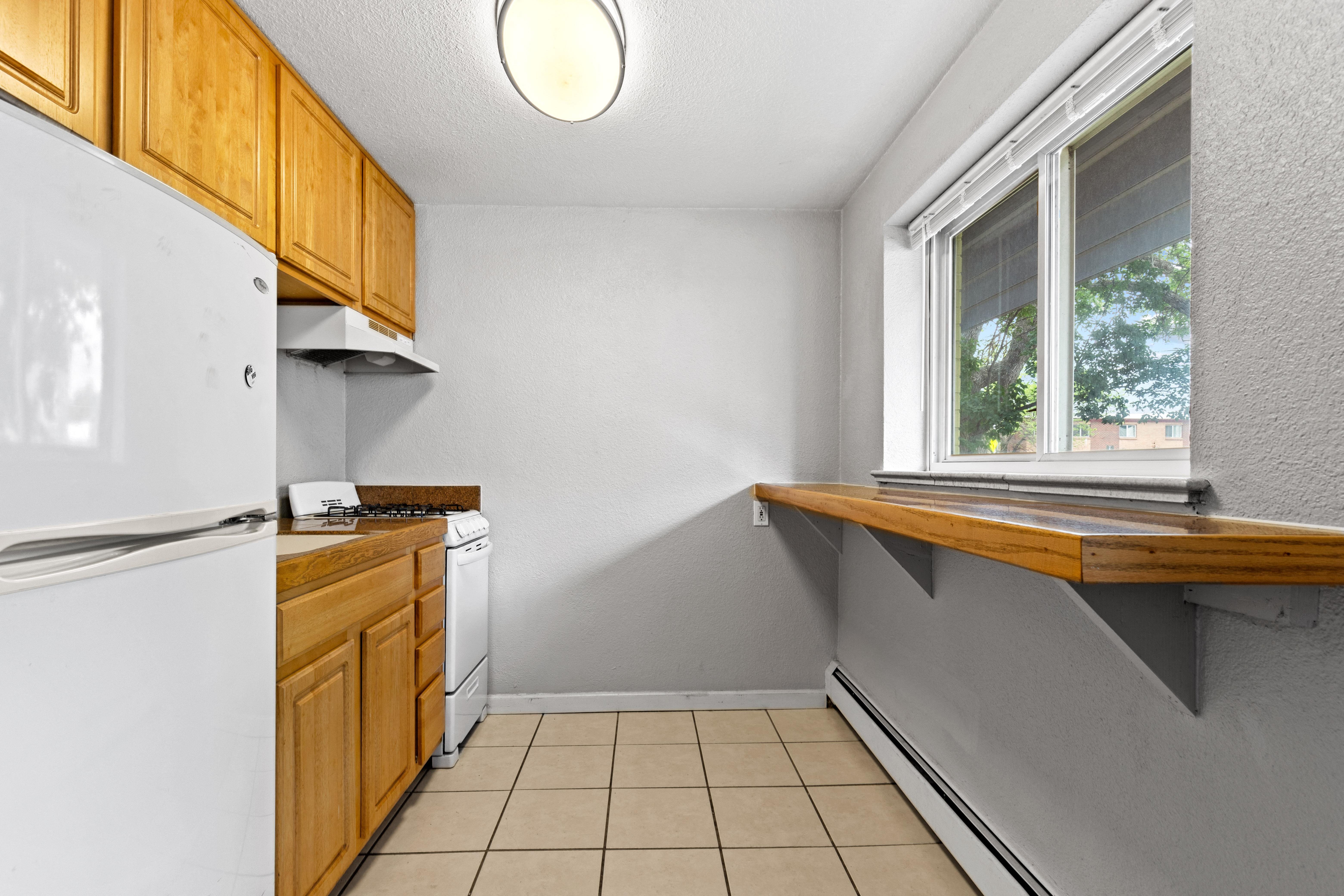 a kitchen with white appliances and wooden cabinets and a window